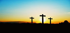 Three crosses on a grassy hill at sunset. Salvation comes only through Jesus Christ.